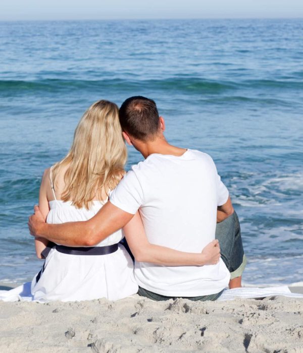 Affectionate couple sitting on the sand at the beach