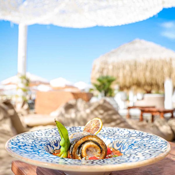 A vertical shot of a gourmet fish dish at a beachside restaurant